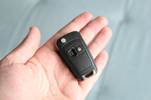 Car key in hand with missing button.