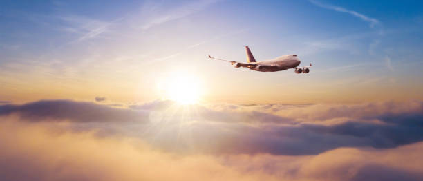 Commercial airplane flying over dramatic sunset