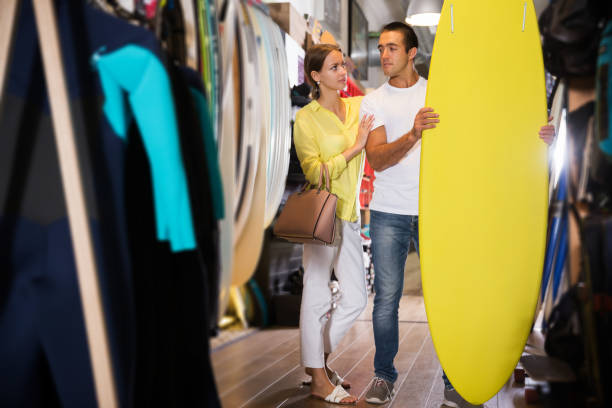 istock couple choosing surfboard in sporting goods store 1200799611