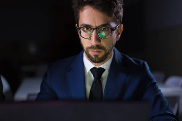 istock Focused man sitting at table with laptop and looking at camera 1200800799