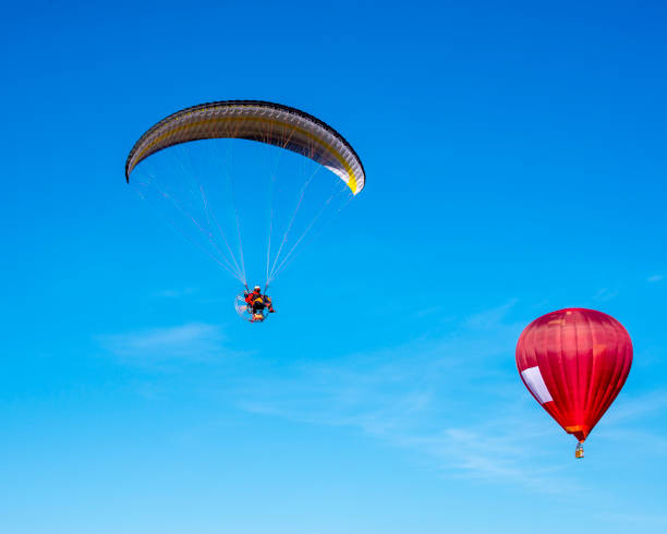 istock Paraglider with red hot air balloon 1200802954