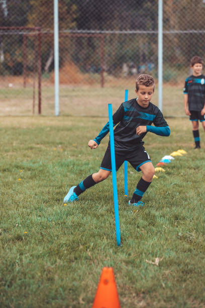 istock Boy in uniform exercising during football training on green lawn 1200806475