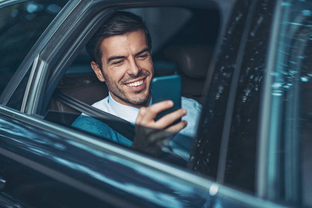 hombre de negocios con un teléfono celular en el asiento trasero de un coche - direct view fotografías e imágenes de stock