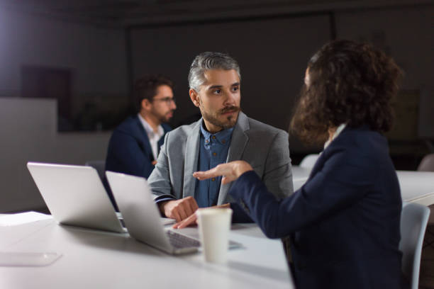 istock Coworkers discussing work in dark office 1200807675