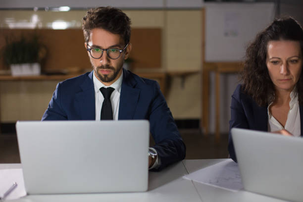 istock Front view of focused business people working with laptops 1200809443