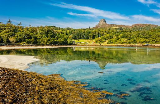 Isle of Eigg, Small Isles, Hebrides, Scotland.  A beautiful bay at low tide with silver sands and An Sgurr in the background and reflected in the clear blue waters. Landscape, Horizontal, space for copy