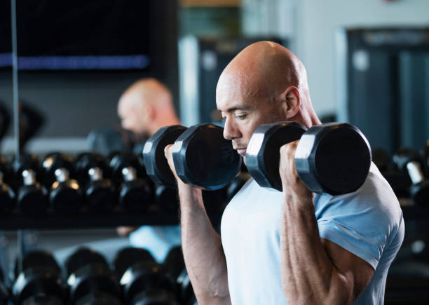 istock Hispanic man working out at gym lifting dumbbells 1200813179