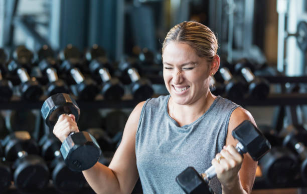 istock Hispanic woman working out at gym, lifting dumbbells 1200813406