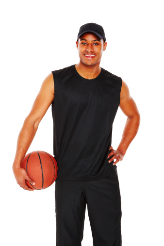 Attractive young man smiles while holding a basketball to his hip. Isolated on white.