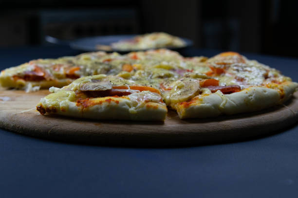 istock Pizza on a wooden board which stands on a beautiful black background 1200815532
