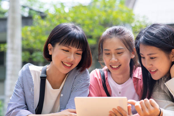 istock Three Asian women looking at digital tablet screen in public park 1200817765