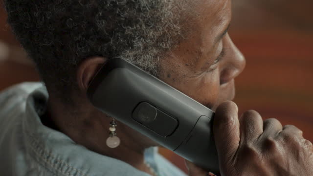 Older black woman talking on a cordless landline phone - OTS