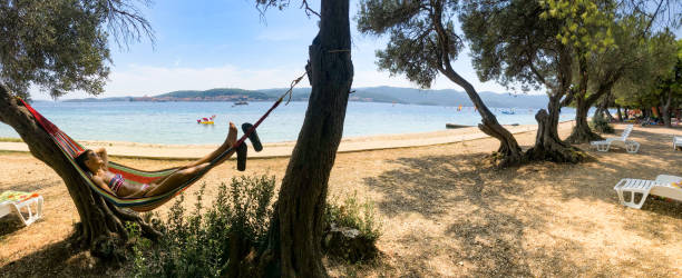 Tourist Relaxing in Hammock on Beach.