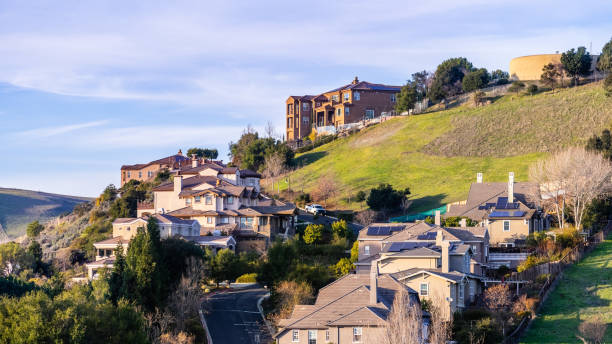 quartier résidentiel avec maisons unifamiliales à plusieurs niveaux, construit sur une zone vallonnée; réservoir d'eau visible au sommet de la colline; hayward, east san francisco bay area, californie - house residential structure california mansion photos et images de collection