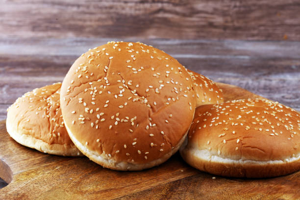 istock Buns with sesame. Fresh homemade burger buns on table. 1200833303