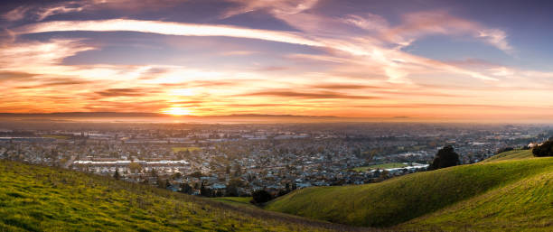 Sunset view of residential and industrial areas in East San Francisco Bay Area; green hills visible in the foreground; Hayward, California Sunset view of residential and industrial areas in East San Francisco Bay Area; green hills visible in the foreground; Hayward, California alameda county stock pictures, royalty-free photos & images