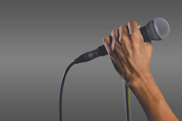 istock Man hand holding a microphone on a stand. The microphone clipping path. 1200835730