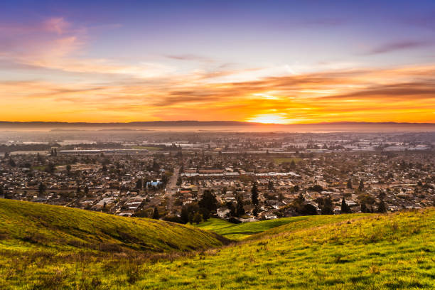 sonnenuntergangsansicht von wohn- und industriegebieten in east san francisco bay area; grüne hügel im vordergrund sichtbar; hayward - san francisco bay area community residential district california stock-fotos und bilder