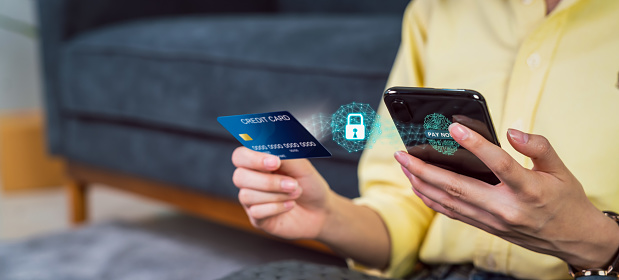 Woman holding smartphone and credit card with scanning biometric fingerprint for approval to access for payment mobile banking on application wallet.