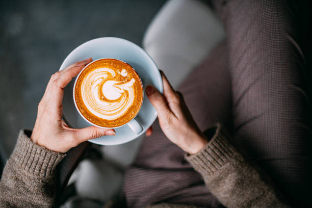 flat lay woman hand holding coffee latte - cappuccino imagens e fotografias de stock
