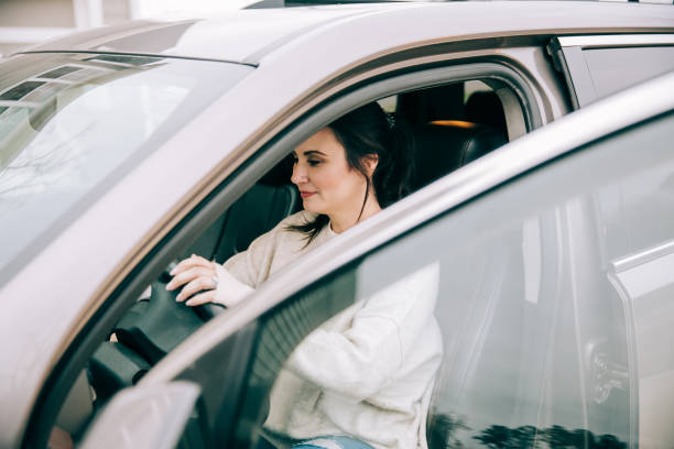 istock dark haired brunnette woman getting into a modern tan sedan car 1200844683