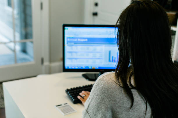 widok z tyłu brunetka kobieta biznesu pracuje na komputerze w małym, głównie białym nowoczesnym biurze domowym - rear view computer monitor computer office zdjęcia i obrazy z banku zdjęć
