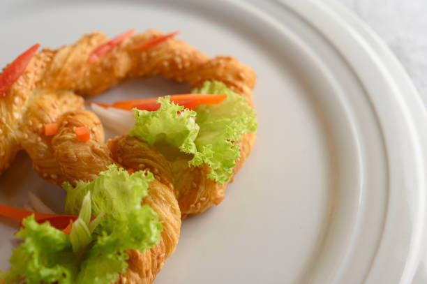 Close up Freshly baked soft pretzel with generous sprinkling of coarse salt and sesame on white dish, decorate with lettuce and carrot beautifully, copy space