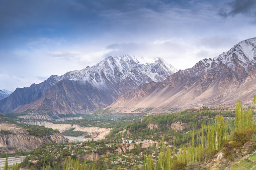 view of the Pakistani Karakorum mountains, K2 and Nanga Parbat. Clouds partly hide mountains, valleys and glaciers.