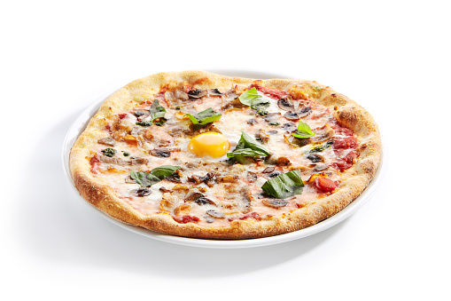 Pizza with mushrooms, bacon and egg on white restaurant plate isolated. Italian carbonara pizza with mushrooms, tomatoes and fresh green basil closeup