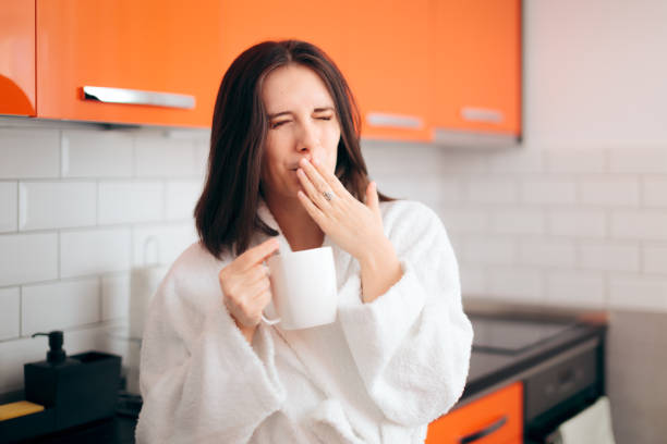 istock Sleepy Woman in Bathrobe Holding Coffee Mug 1200860683