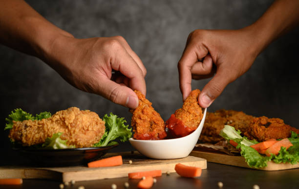 Two hand holding crispy fried chicken dipped in tomato sauce.Selective focus. stock photo