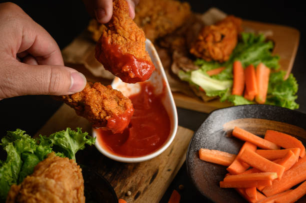 istock Hand holding crispy fried chicken dipped in tomato sauce. Selective focus. 1200861555