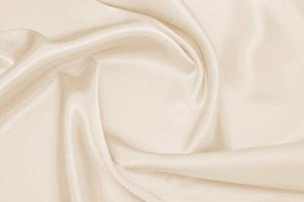 istock Draped satin beige fabric for festive backgrounds 1200862095