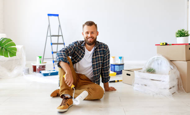 istock Repair in apartment. Happy man paints wall 1200862890