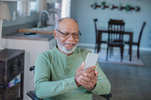 istock Senior male looking at cell phone while sitting in kitchen 1200863078
