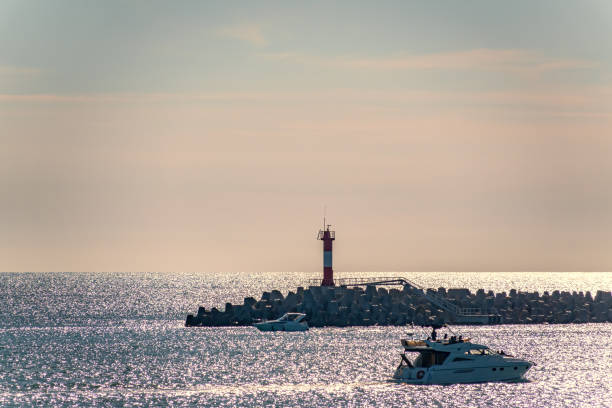 istock Clear sky and bright sunset over the sea with a breakwater and a lighthouse 1200864177