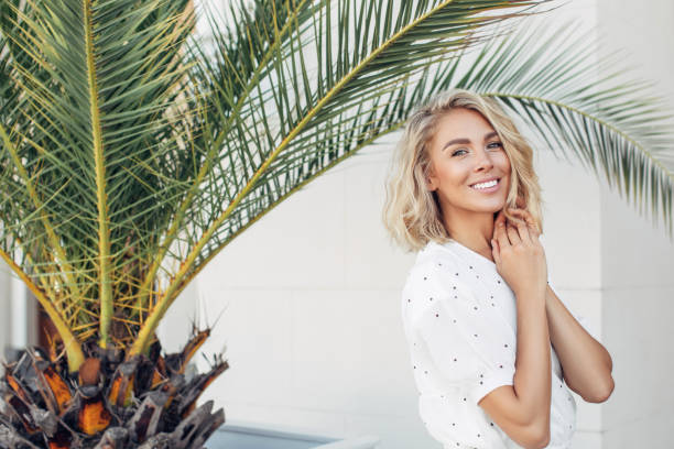 glückliches mädchen zu fuß in der nähe von palmen an einem sommer sonnigen tag - blondes haar fotos stock-fotos und bilder