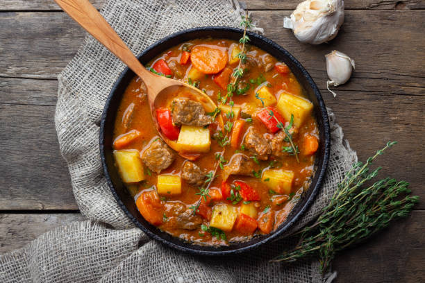 goulash, guisado de carne ou sopa de bogrash com carne, legumes e especiarias em panela de ferro fundido na mesa de madeira. - soup photography pan hungary - fotografias e filmes do acervo