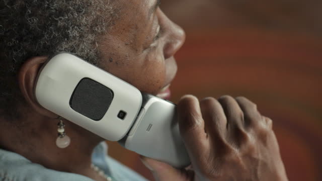 Happy friendly senior black woman opening a flip phone and talking - OTS
