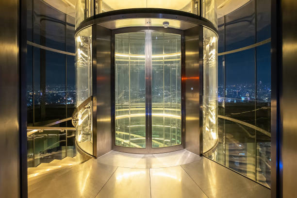 forme cylindrique moderne d'ascenseur en verre - lighting equipment office building night city photos et images de collection