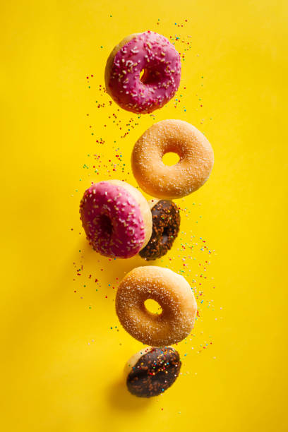 istock Various decorated doughnuts with sprinkles in motion falling on yelloy background 1200881889