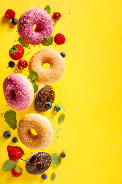 istock Various decorated doughnuts with sprinkles and berries in motion falling on yelloy background 1200881892