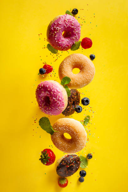 istock Various decorated doughnuts with sprinkles and berries in motion falling on yelloy background 1200881909