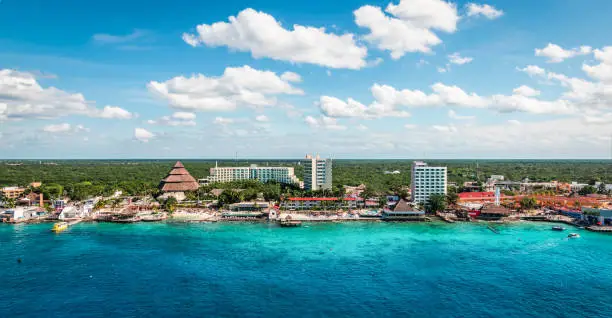 Panoramic view of popular cruise and tourist destination with buildings along the coastline at the port of Cozumel in Mexico. Blue sky and clouds. Beautiful summer day. Caribbean Sea with turquoise colored water.