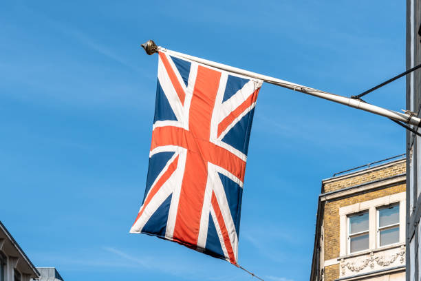 istock Union Jack UK flag waving against blue sky 1200888306