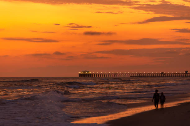 A couple in love walks on the beach in California during a beautiful sunset by the pier