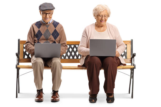 istock Elderly man and woman on a bench with laptop computers 1200888782