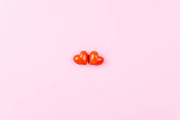 istock Two glossy red hearts on a pink background. Minimalism 1200890878