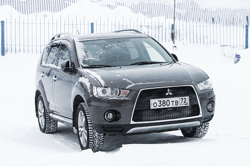 Pangody, Russia - January 20, 2020: Grey crossover Mitsubishi Outlander in the town street during a snowfall.