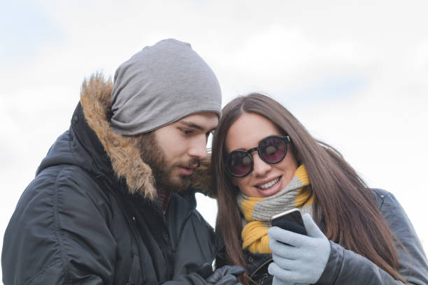 istock Couple using cellphone in cold winter times outdoors. 1200893000